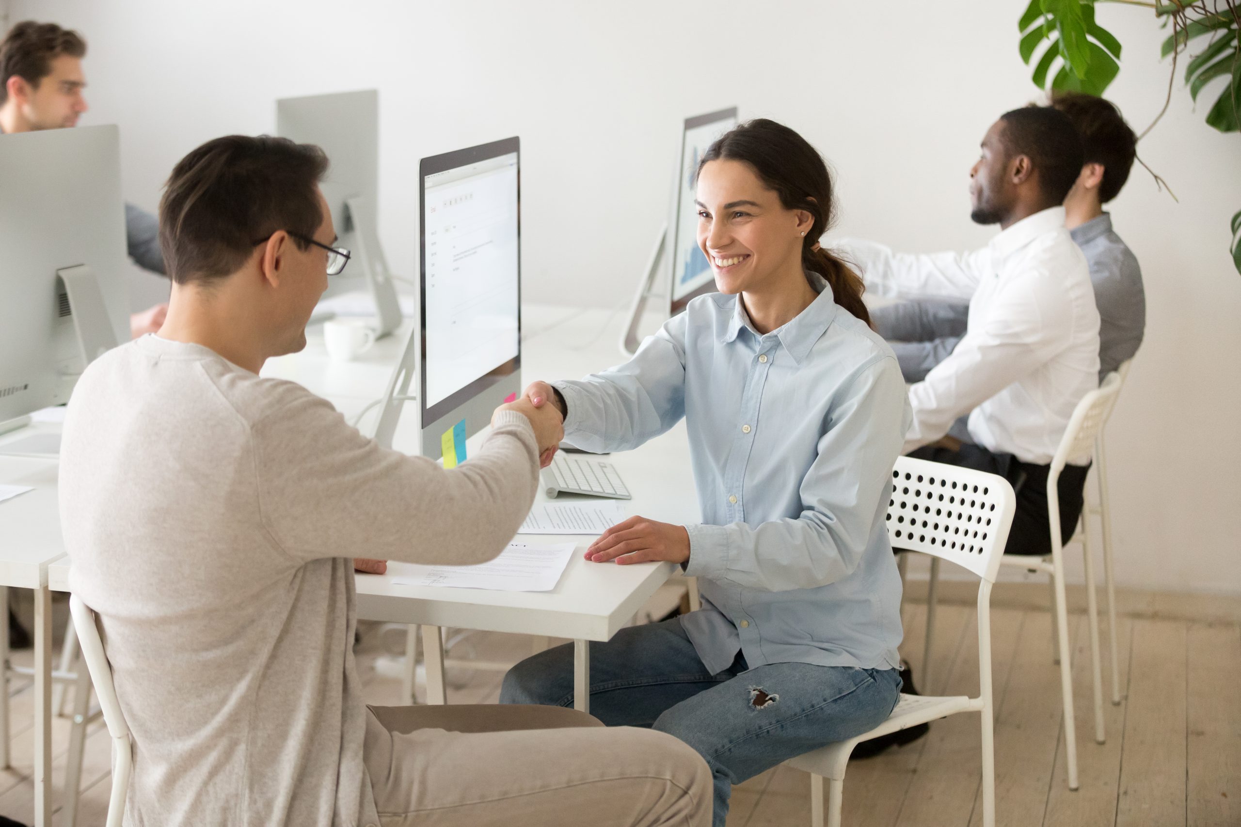 smiling young woman handshaking satisfied client making deal office scaled