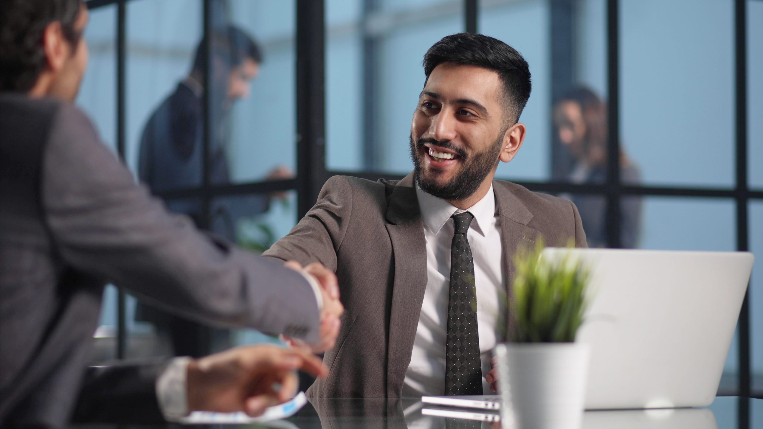 happy business partners shaking hands negotiating table scaled