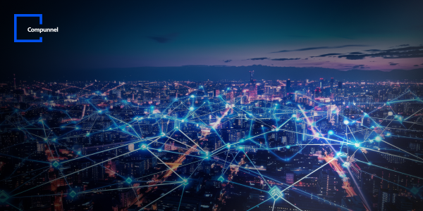  This image features a panoramic night view of a bustling cityscape with dense urban lighting. Overlaid on the city is a network of bright blue and white lines and nodes, simulating a digital connectivity grid or smart city concept. The lines intersect at various nodes, suggesting data exchange or communication points. The sky transitions from a deep twilight blue to a darker hue, adding to the scene's futuristic vibe. The "Compunnel" logo is positioned in the upper left corner against the dark sky.
