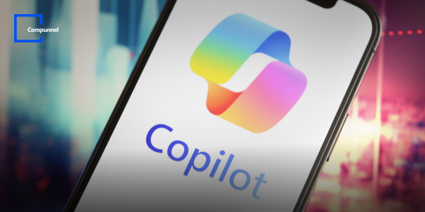 Close-up view of a smartphone screen displaying the colorful Copilot logo, indicating an AI-powered assistant. The background is blurred with vibrant lights, highlighting the focus on the Copilot application. Compunnel logo is visible in the top left corner.